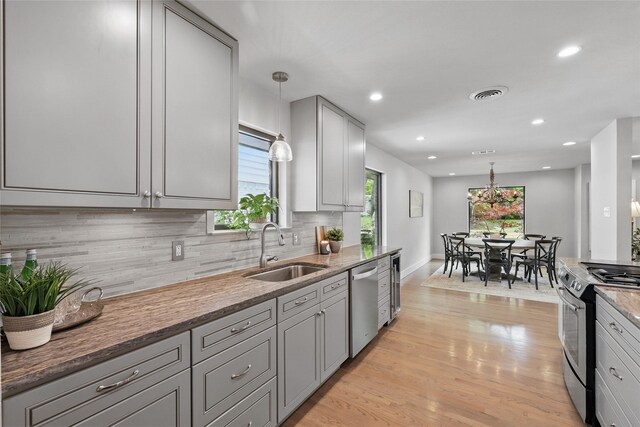 11641 Sasanqua Ln, Dallas, TX 75218 - kitchen with appliances with stainless steel finishes, a sink, gray cabinetry, decorative backsplash, and pendant lighting