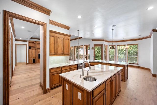 520 Round Hollow Ln, Southlake, TX 76092 - kitchen featuring brown cabinets, a center island with sink, crown molding, light wood finished floors, and light stone counters