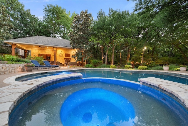 view of pool with a pool with connected hot tub, a storage structure, an outbuilding, and a patio area
