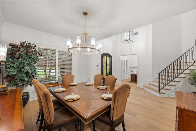 dining space featuring a chandelier, light wood-style floors, stairs, and ornamental molding
