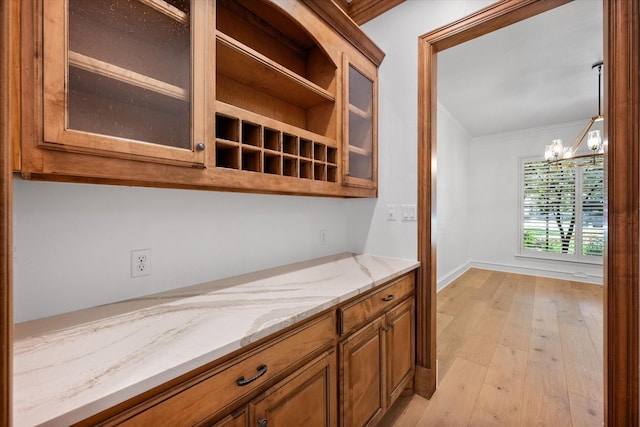 520 Round Hollow Ln, Southlake, TX 76092 - kitchen featuring a chandelier, brown cabinetry, light stone counters, light wood-type flooring, and glass insert cabinets