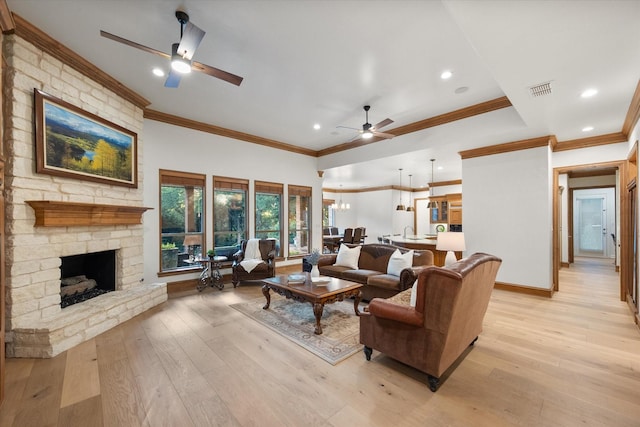 living room with a ceiling fan, ornamental molding, light wood-style flooring, a stone fireplace, and baseboards