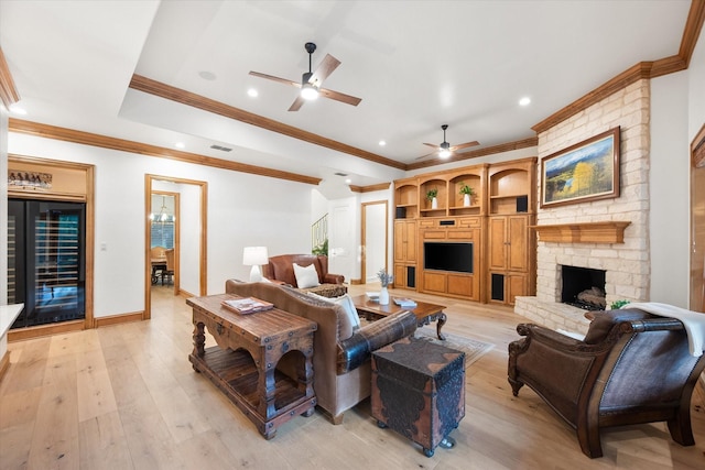 living room featuring beverage cooler, a ceiling fan, crown molding, light wood-type flooring, and a fireplace