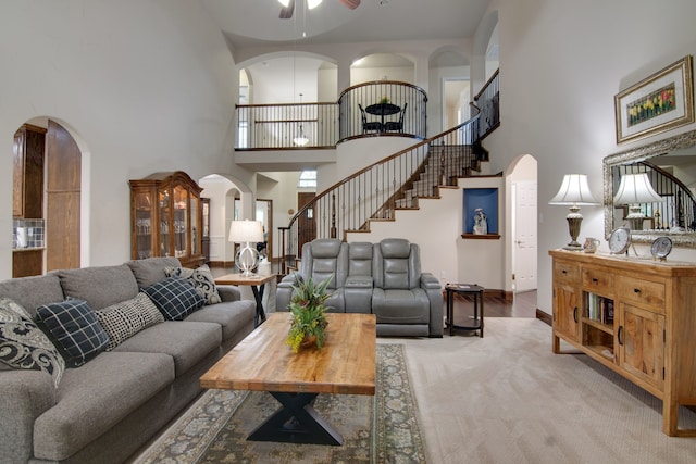 6001 Lacebark Elm Dr, Fort Worth, TX 76123 - carpeted living room featuring a high ceiling, arched walkways, a ceiling fan, stairs, and baseboards