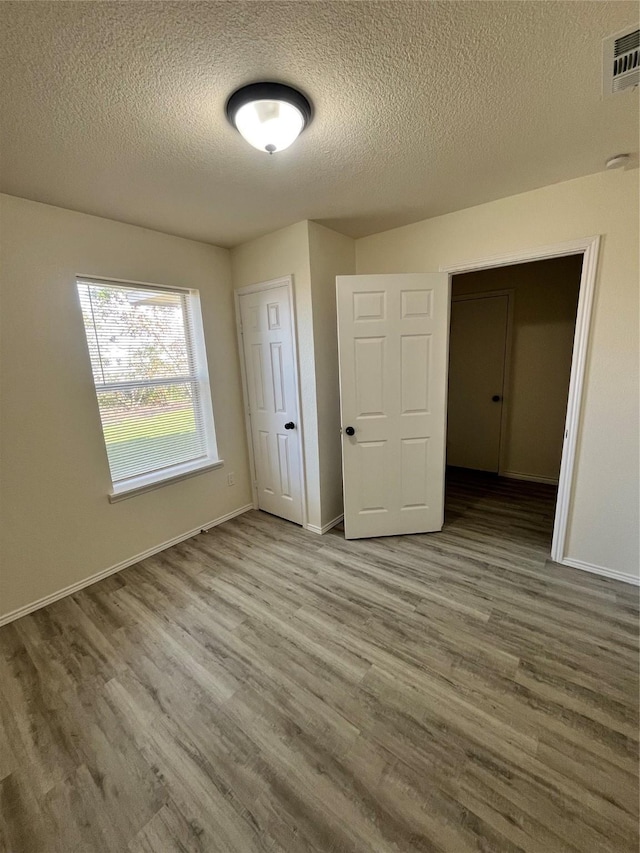 6706 Frontage Rd, Greenville, TX 75402 - unfurnished bedroom with wood finished floors, a textured ceiling, and baseboards