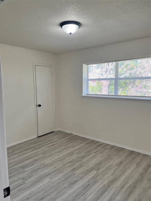 6706 Frontage Rd, Greenville, TX 75402 - spare room with a textured ceiling, light wood-style floors, and baseboards