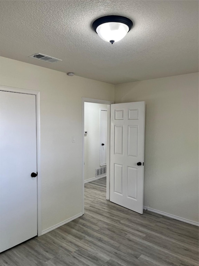 6706 Frontage Rd, Greenville, TX 75402 - spare room featuring wood finished floors, a textured ceiling, and baseboards