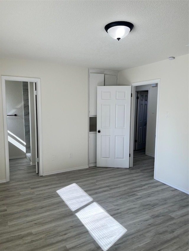 6706 Frontage Rd, Greenville, TX 75402 - unfurnished bedroom with wood finished floors, baseboards, and a textured ceiling