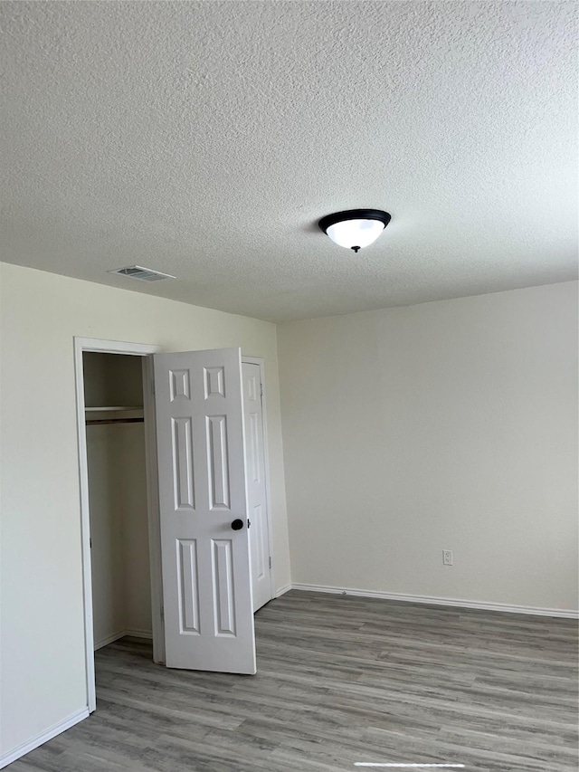 6706 Frontage Rd, Greenville, TX 75402 - unfurnished bedroom with wood finished floors, a textured ceiling, a closet, and baseboards
