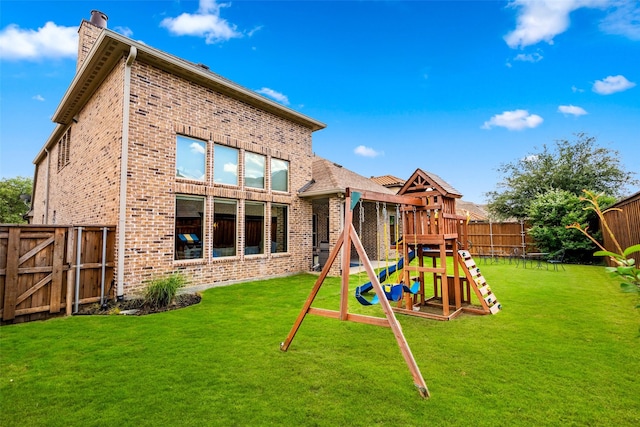 3713 Adelaide, The Colony, TX 75056 - rear view of property featuring a chimney, brick siding, and a playground