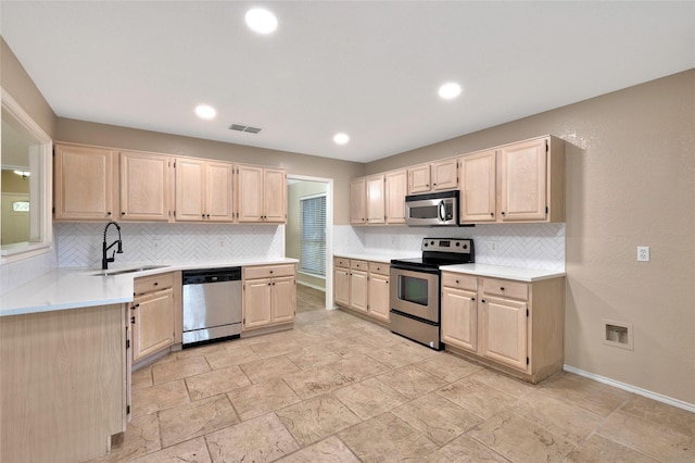 kitchen with appliances with stainless steel finishes, light brown cabinetry, a sink, tasteful backsplash, and recessed lighting