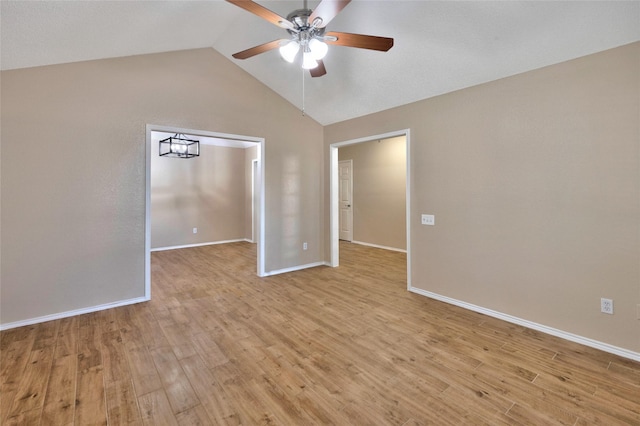 spare room featuring a ceiling fan, light wood finished floors, vaulted ceiling, and baseboards