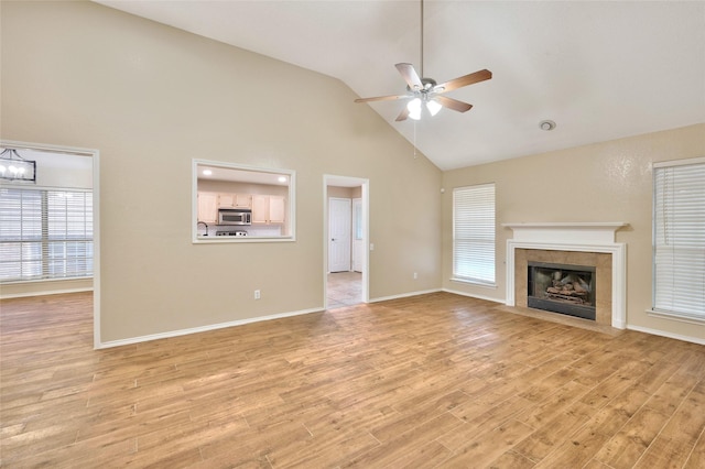 unfurnished living room with a ceiling fan, high vaulted ceiling, light wood-style flooring, a fireplace, and baseboards