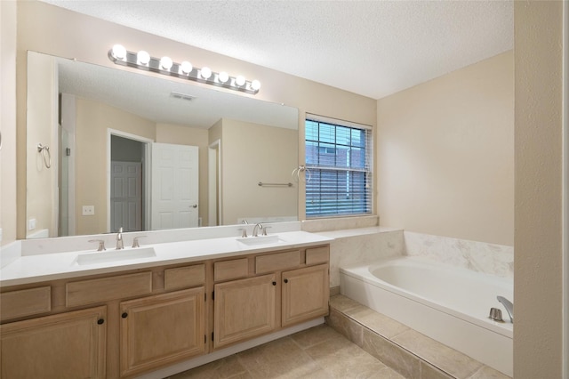 bathroom with a garden tub, double vanity, a textured ceiling, and tile patterned floors