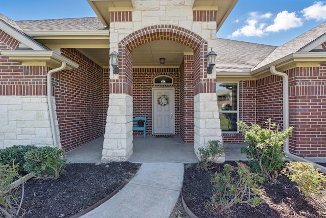 711 Red Stone Ln, Weatherford, TX 76087 - doorway to property featuring brick siding, a shingled roof, stone siding, and a porch