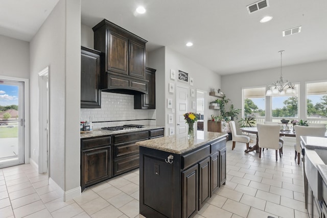 711 Red Stone Ln, Weatherford, TX 76087 - kitchen with decorative backsplash, light tile patterned flooring, light stone counters, a chandelier, and recessed lighting