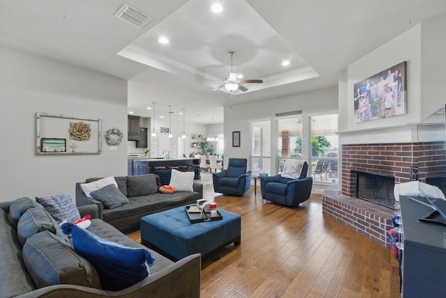 711 Red Stone Ln, Weatherford, TX 76087 - living room with a tray ceiling, a ceiling fan, hardwood / wood-style flooring, a brick fireplace, and recessed lighting
