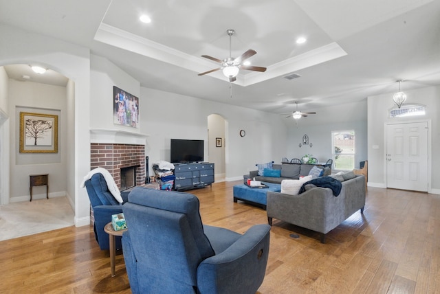 711 Red Stone Ln, Weatherford, TX 76087 - living area featuring a tray ceiling, arched walkways, light wood-type flooring, ceiling fan, and a fireplace