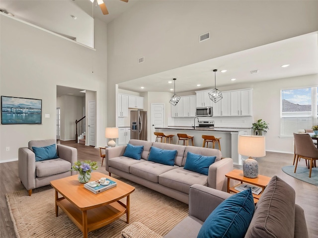 8998 Delway Dr, Providence Village, TX 76227 - living room with light wood-type flooring, ceiling fan, baseboards, recessed lighting, and a towering ceiling