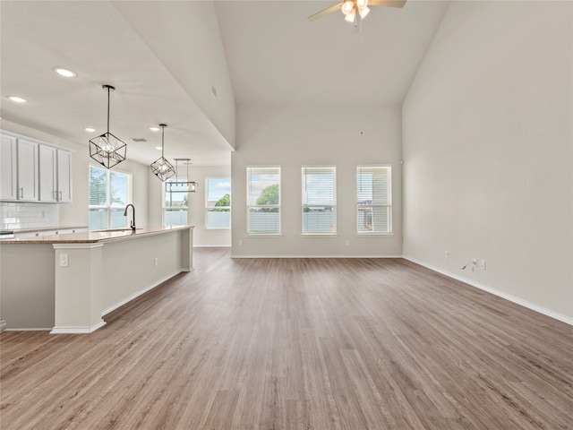 8998 Delway Dr, Providence Village, TX 76227 - unfurnished living room featuring light wood finished floors, baseboards, a ceiling fan, recessed lighting, and a chandelier