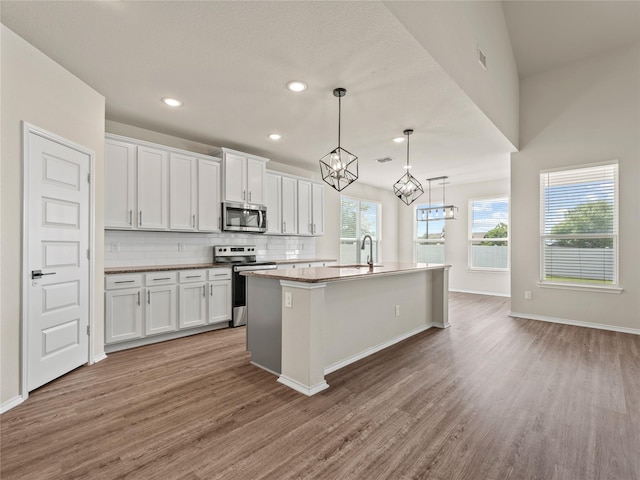 8998 Delway Dr, Providence Village, TX 76227 - kitchen featuring stainless steel appliances, wood finished floors, backsplash, white cabinetry, and recessed lighting