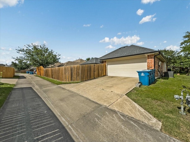 6705 Westover Dr, Rowlett, TX 75089 - view of side of property with driveway, central AC unit, brick siding, a garage, and roof with shingles