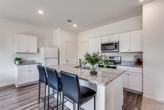 2115 Revere Dr, Princeton, TX 75407 - kitchen featuring stainless steel appliances, baseboards, white cabinetry, a kitchen island with sink, and light stone countertops