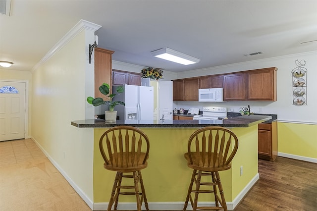 819 Earhart Ave, Grand Prairie, TX 75051 - kitchen featuring white appliances, a kitchen breakfast bar, a peninsula, ornamental molding, and dark countertops