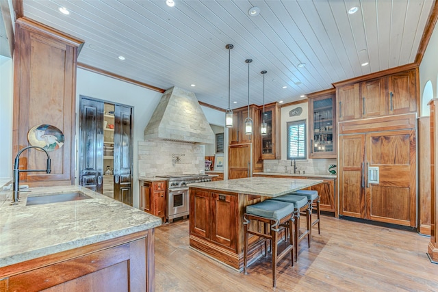 kitchen with a sink, premium range hood, recessed lighting, high end stainless steel range, and crown molding