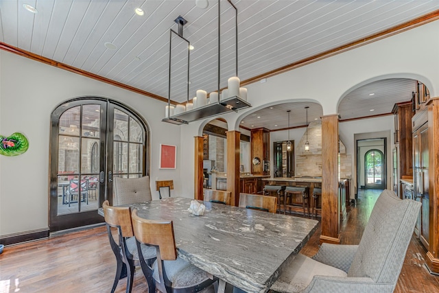 dining room with wood finished floors, ornamental molding, recessed lighting, french doors, and arched walkways