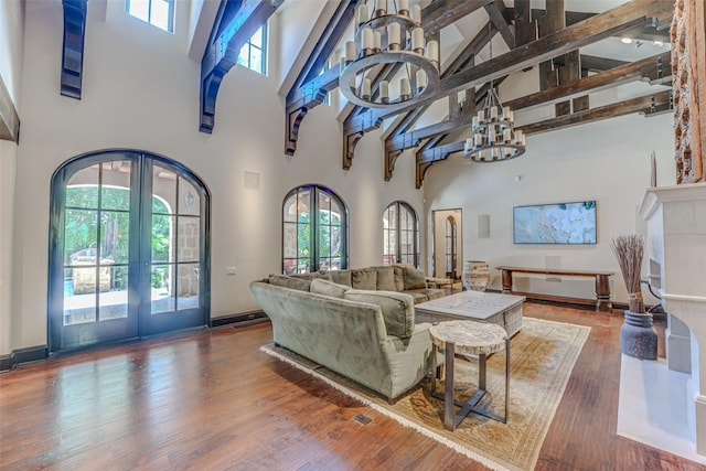 living room with french doors, a high ceiling, plenty of natural light, wood finished floors, and beamed ceiling