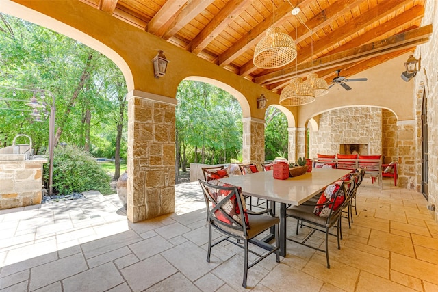 view of patio featuring an outdoor stone fireplace, outdoor dining space, and a ceiling fan