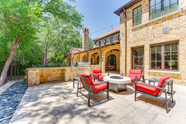 view of patio / terrace with exterior kitchen, an outdoor fire pit, and a grill