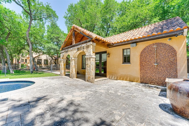 back of property featuring a tiled roof, stucco siding, fence, and a patio