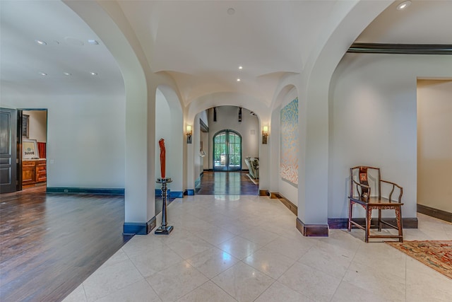 hall with recessed lighting, arched walkways, tile patterned flooring, and baseboards