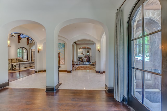 hallway featuring tile patterned flooring, baseboards, and arched walkways