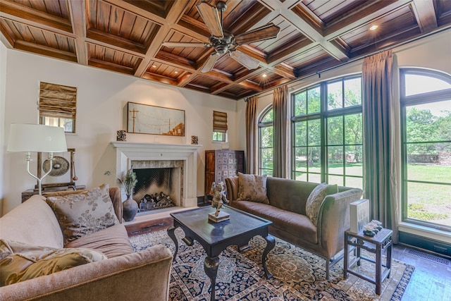 living area with wooden ceiling, a ceiling fan, a fireplace with raised hearth, coffered ceiling, and beamed ceiling