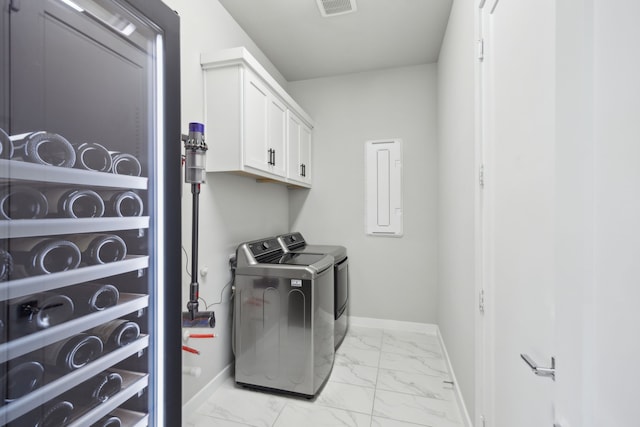 washroom with baseboards, light marble finish floors, independent washer and dryer, and cabinet space