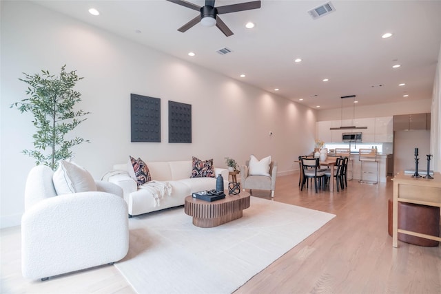 living room with recessed lighting, light wood-type flooring, ceiling fan, and baseboards