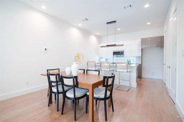dining room featuring light wood finished floors, recessed lighting, and baseboards