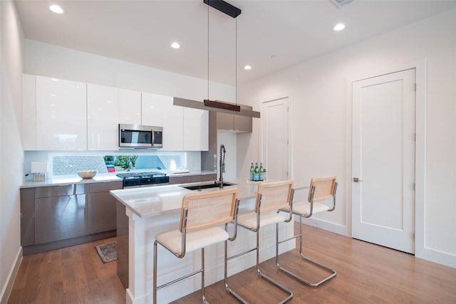 kitchen featuring stainless steel microwave, a sink, modern cabinets, range, and white cabinets