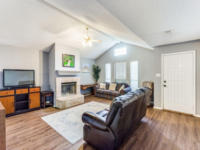 202 Lancelot Dr, Weatherford, TX 76086 - living area featuring light wood finished floors, a ceiling fan, lofted ceiling, a fireplace, and a textured ceiling