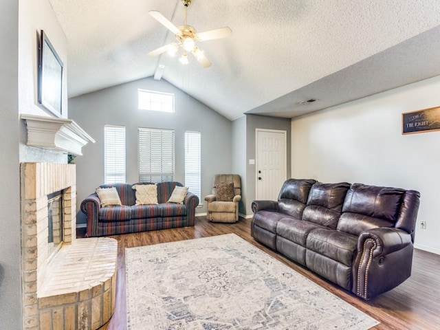 202 Lancelot Dr, Weatherford, TX 76086 - living room with vaulted ceiling, a ceiling fan, wood finished floors, a textured ceiling, and a fireplace