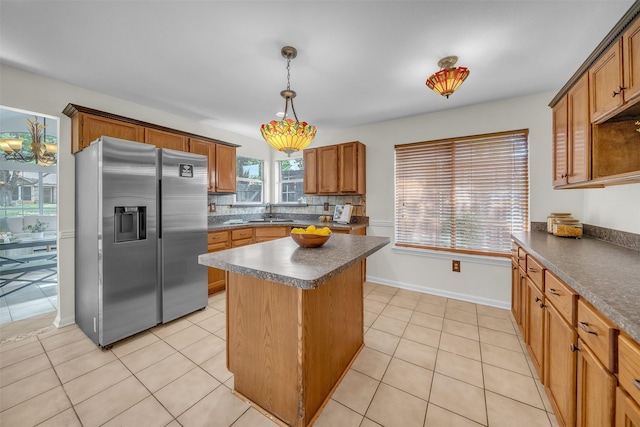 2802 Glen Ridge Dr, Arlington, TX 76016 - kitchen with stainless steel fridge with ice dispenser, dark countertops, light tile patterned floors, brown cabinetry, and a center island