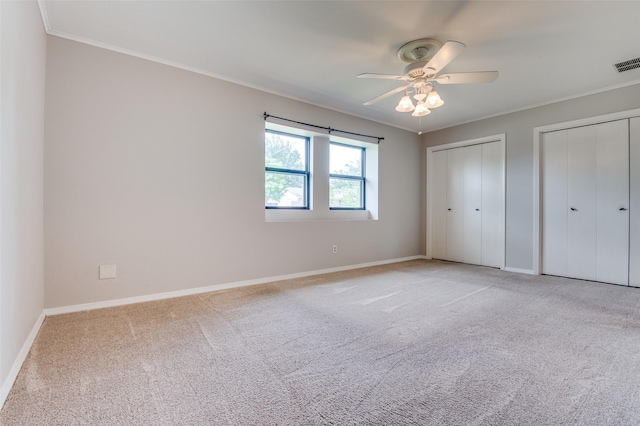 2800 Peachtree Ln, Pantego, TX 76013 - unfurnished bedroom featuring two closets, ornamental molding, light carpet, baseboards, and ceiling fan