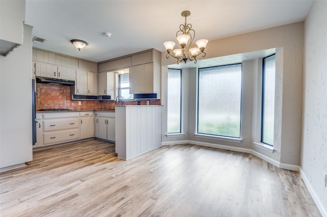 2800 Peachtree Ln, Pantego, TX 76013 - kitchen with tasteful backsplash, range hood, a chandelier, light wood-style floors, and decorative light fixtures