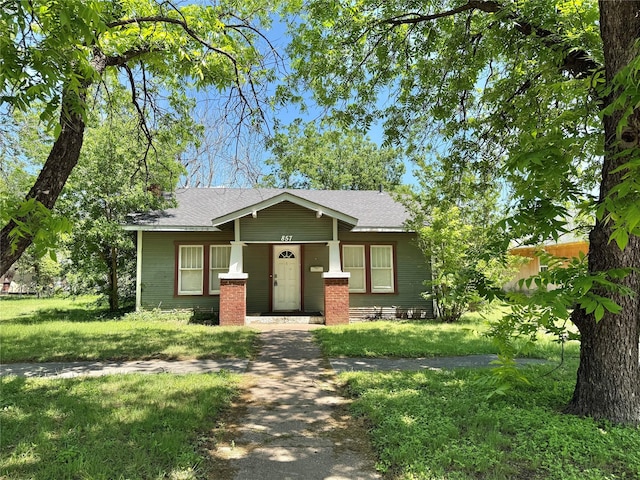 view of front facade with a front lawn and a shingled roof