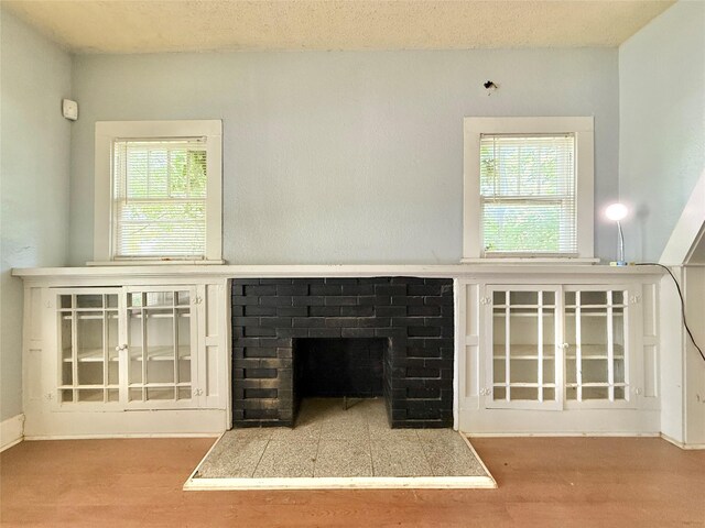 unfurnished living room with wood finished floors, a fireplace, and plenty of natural light