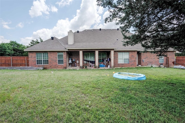 rear view of property featuring brick siding, a patio area, a chimney, and roof with shingles