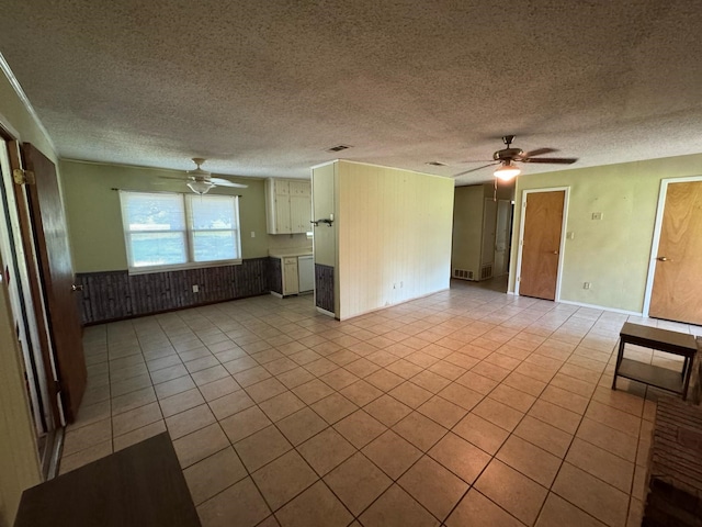 1946 US Highway 380 E, Graham, TX 76450 - unfurnished living room featuring ceiling fan, light tile patterned floors, a textured ceiling, and a wainscoted wall